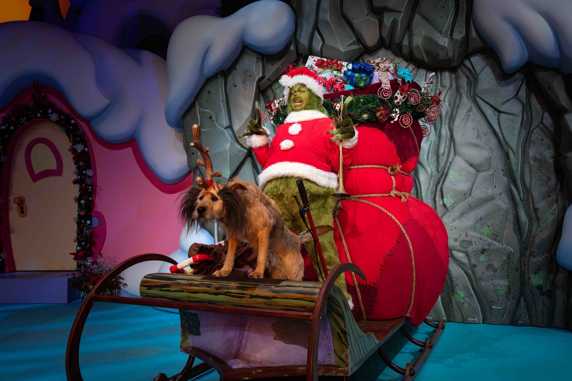 grinch in santa outfit with sleigh full of presents